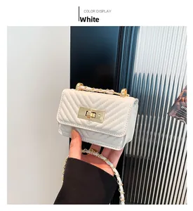 Close-up of white leather crossbody bag with V-shaped quilting and golden chain strap