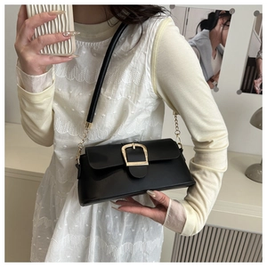 Detailed close-up of a black matte leather underarm bag with a golden square buckle