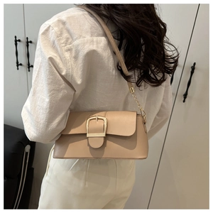 Detail of light beige shoulder bag featuring a large gold buckle and chain strap