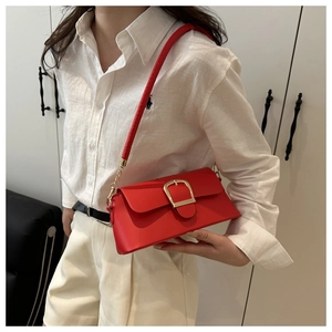 Detail view of red leather underarm bag with oversized gold buckle on model