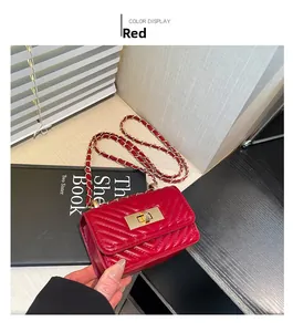 Detail of red patent leather mini crossbody bag with V-quilt pattern and gold metal lock
