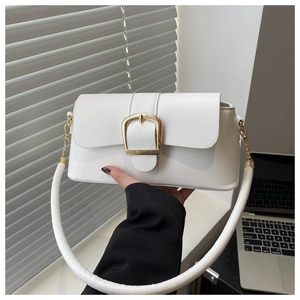 Detail of white leather baguette bag with a bold gold buckle and a wide circular strap