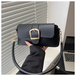 Detail of a black leather handbag featuring a large gold buckle and a cylindrical handle
