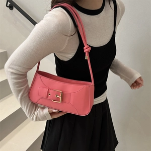 Pink minimalist underarm bag with knot strap and gold buckle worn by a model