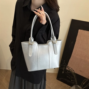 Fashionable silver pleated handbag with golden metal rings and leather texture