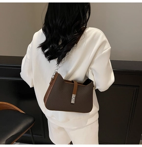 Detailed close-up of dark brown woven underarm bag with cat-ear shape and metal buckle