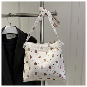 Détail d'un sac en toile blanc avec bordure en dentelle fleurie et imprimé koala