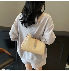 Beige woven shoulder bag with silver clasp and leather trim shown from a back view