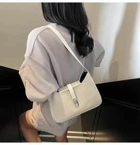 Detail of cream herringbone underarm bag with leather trim and silver clasp on a model
