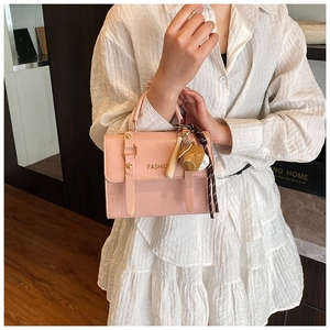 Close-up of pink patent leather crossbody bag with gold rivets and fashion charm