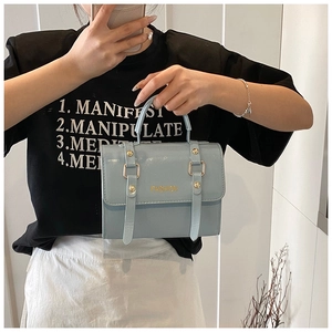 Close-up of light blue crossbody bag with gold buckle and textured leather finish