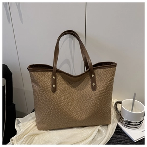 Detail of woven texture and crocodile pattern on brown tote with gold rivets