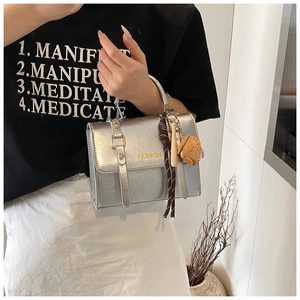 Detail of silver metallic handbag with FASHION text and baseball glove charm accessory