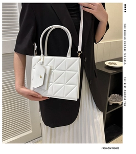 Detail of white quilted handbag with a matching mini envelope pouch and slim strap