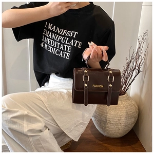 Close-up of a glossy dark brown patent leather handbag with gold buckle and fashion logo