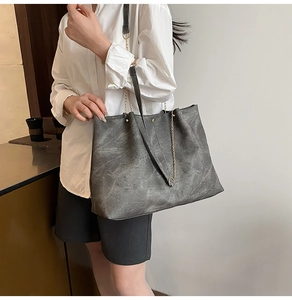 Detail of soft charcoal tote bag with marble texture and golden chain strap for women