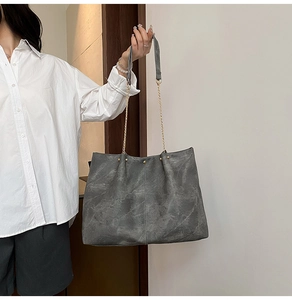 Close-up of a vintage grey tote bag showing textured soft leather and metal chain handle
