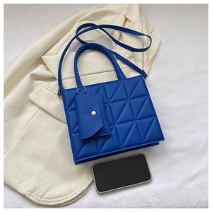 Detail of blue quilted handbag with triangular pattern and mini pouch on white suit