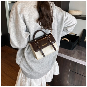 Detail view of contrast color crossbody bag with brown flap and fashion gold lettering