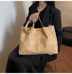 Detail of khaki soft leather tote bag with gold chain handle and vertical stitching