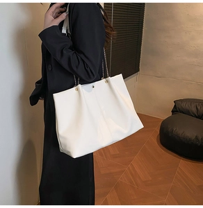 Detailed view of the white soft leather tote bag with chain strap and metal rivet accents
