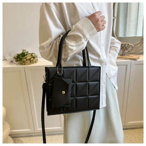 Detail of black quilted handbag with mini pouch accessory and detachable shoulder strap