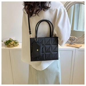 Detail of black quilted handbag with geometric pattern and detachable mini pouch accessory