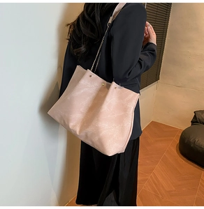 Detail of soft leather tote bag with elegant golden chain strap and magnetic closure