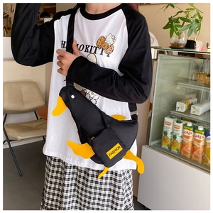 Detail of creative black duck-shaped canvas crossbody bag with yellow beak and wings