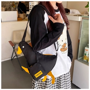 Detail of cute duck-shaped black canvas crossbody bag showing strap and fashion label