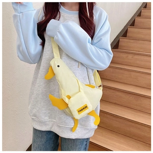 Cute yellow canvas duck crossbody bag with adjustable strap worn by a model on stairs