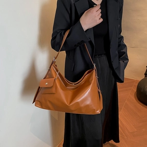 Caramel brown large leather hobo bag with mini pouch charm worn by a model in black