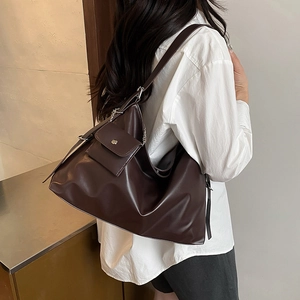 Minimalist dark coffee leather tote bag with silver chain detail on a model