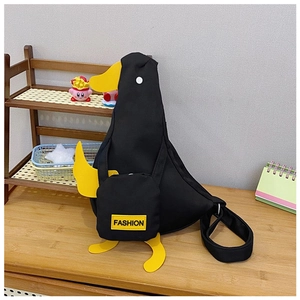 Detail of cute duck-shaped black canvas bag with yellow fashion tag on wood table