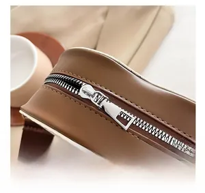 Gros plan sur le sac en cuir PU marron mat montrant la fermeture éclair en métal argenté