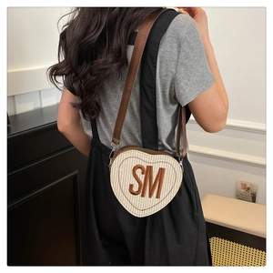 Détail du sac bandoulière tissé en forme de cœur avec broderie SM marron et sangle