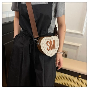 Gros plan d'un sac à bandoulière tissé en forme de cœur avec initiales SM brodées