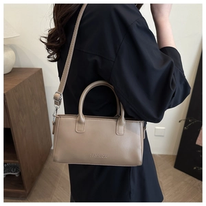 Detail of khaki leather handbag featuring embossed Fashion logo and silver hardware buckle