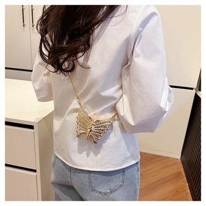 Detail of a golden butterfly crossbody bag with sparkling rhinestones and metal chain strap