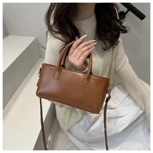 Dettaglio di borsa marrone in pelle PU con scritta Fashion e tracolla sottile regolabile