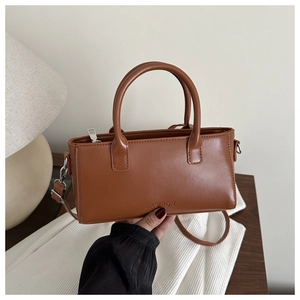 Dettaglio di una borsa a tracolla marrone con logo FASHION goffrato e doppi manici eleganti