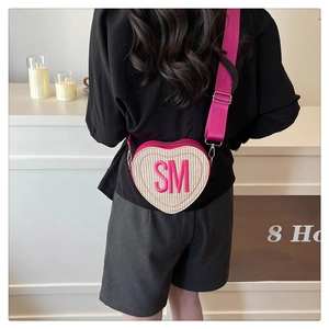 Détail du sac bandoulière en forme de cœur avec texture tissée et broderie SM