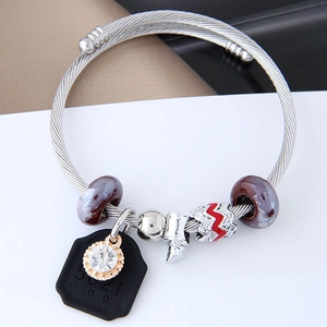 Detail of twisted cable steel bracelet featuring purple beads and a zircon tag pendant
