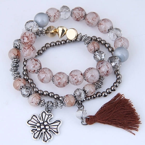 Close-up of bohemian multilayer beaded bracelet with silver flower charm and brown tassel
