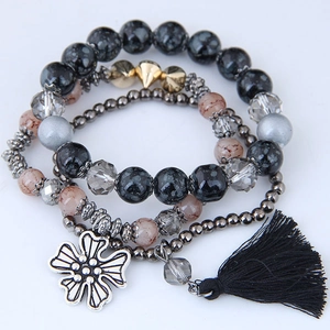 Detail of bohemian multilayer bracelet with marble beads, silver charm, and black silk tassel