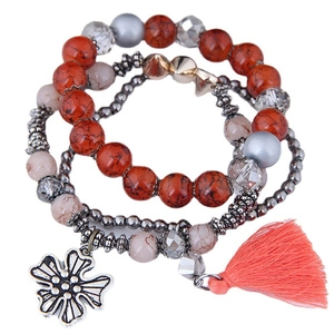 Three-piece layered beaded bracelet set with floral charm and pink tassel accents