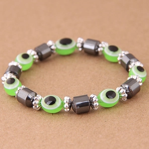 Dettaglio macro del bracciale con mano di Fatima, occhio greco verde ed ematite