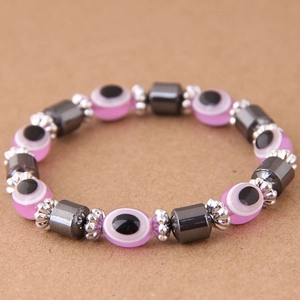 Dettaglio delle perle occhio di Allah rosa e cilindri di ematite su bracciale elastico