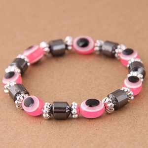 Dettaglio di un braccialetto con perline rosa malocchio e pietre cilindriche in ematite