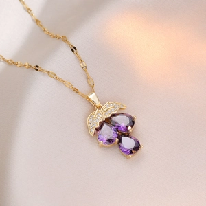 Elegant gold leaf and purple zircon grape pendant necklace on soft silk background